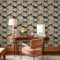 May include: A curved wooden desk with a lamp, a vase of flowers, and a mirror, positioned against wallpaper featuring a repeating pattern of pink peacocks on a dark teal background. A pink upholstered chair with fringe sits in front of the desk.